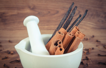 Vintage photo, Fragrant cinnamon and vanilla sticks in mortar on rustic board
