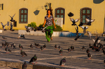 Woman runs down the street through a flock of doves
