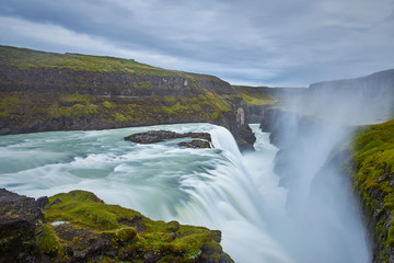 Cloudy sunrise at Gulfoss Iceland with flowing waterfall and big splash of water