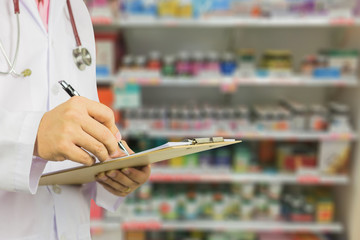 male doctor with stethoscope holding clipboard and writing a prescription,pharmacist writing on...