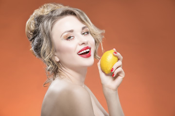 Sexy Fruit Series. Smiling Happy Naked Caucasian Blond Girl With Lemon Fruit. Against Orange Background.