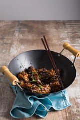 Chicken wings in a Chinese wok. Copy space. Rustic wooden background 