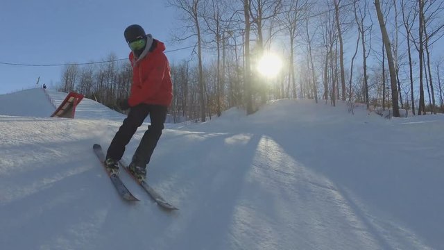 Skier jumps on bendy ledge- awesome sunny follow cam shot