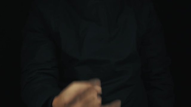 Caucasian male hand in long sleeve jacket, making mano cornuto sign of the horns gesture, on black backround, close up isolated