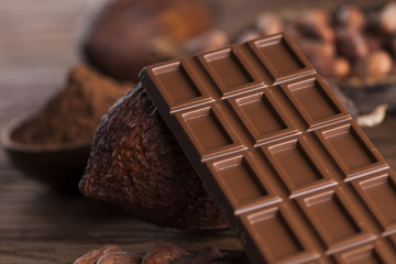 Chocolate bar, candy sweet, cacao beans and powder on wooden background