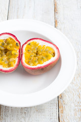 Passion fruit on a white plate closeup on the table.