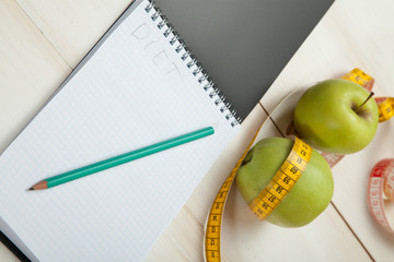 Green apples with measuring tape on a white wooden table