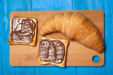 Croissant and toast with chocolate on a blue wooden table