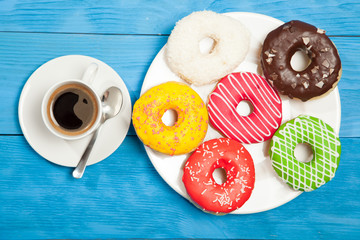 Obraz na płótnie Canvas Cup with coffee and donuts on a blue wooden table