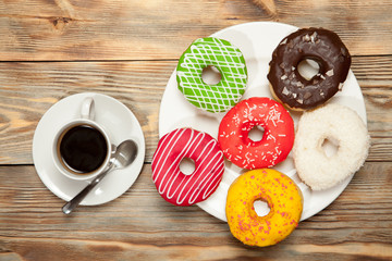 Cup with coffee and donuts on a wooden background