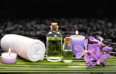 Fototapeta na wymiar tranquil spa scene- purple orchid with candle ,oil green plant, towel