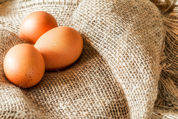 Fresh brown cage free eggs on burlap.