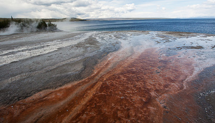 Red sand and geyser steam at Yellowstone Lake