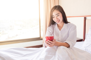 Portrait of a beautiful young lady drinking her morning coffee in her bedroom, Soft light and comfort natural lifestyle.
