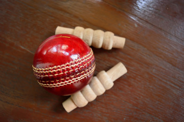 Cricket ball and bails with a shadow on a wooden background