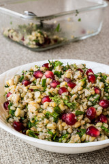 Wheat salad with pomegranate in white bowl.