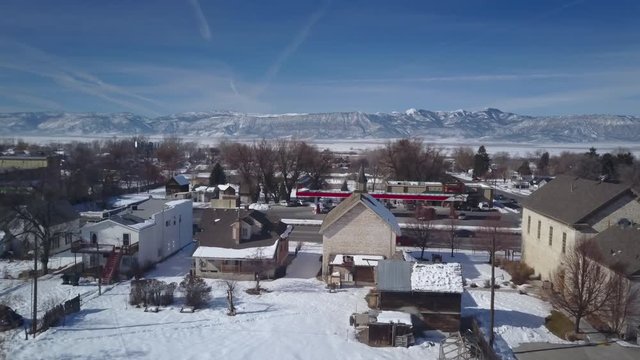 Aerial Ephraim Utah rural town climb to altitude. Aerial point of view. Winter storm blizzard fresh white snow. Rural farm community. Hard seasonal weather. Hazard to driving. Surveillance spy.