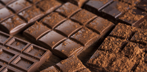 Dark homemade chocolate bars and cocoa pod on wooden
