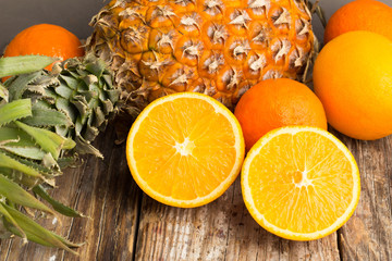 pineapple and oranges close-up on a gray background.