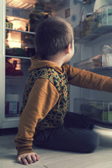 The boy looks in the fridge.