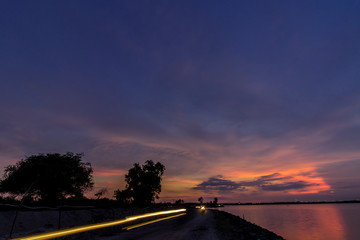 Panorama view with colourful sunset and twilight sky,, tropical island Bali, Indonesia. Dark scene with car and motorbikes lights.
