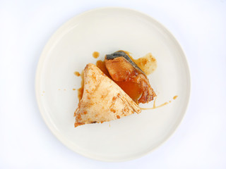 Hamachi cooked in Teriyaki sauce on ceramic plate against white background.