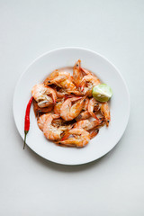 Prepared shrimp with lime on a plate on a gray background top view of a flat