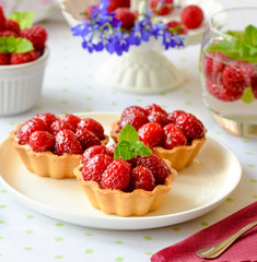 Three cupcakes with raspberries, mint on a table
