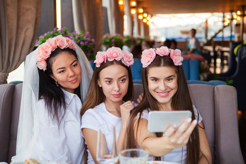 Three happy women taking selfie at hen party in cafe