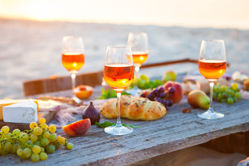 Picnic on the beach at sunset in boho style, food and drink concept
