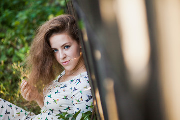 Young woman in simple dress near old fence in a countryside