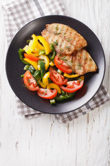 Grilled fish steaks and fresh vegetable salad close-up. vertical top view