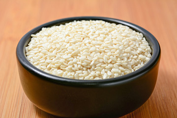 White sesame seeds in black bowl