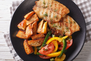 White fish fillet and potato wedges, fresh salad close-up. horizontal top view