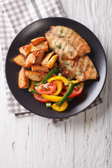 White fish fillet and potato wedges, fresh salad close-up. vertical top view