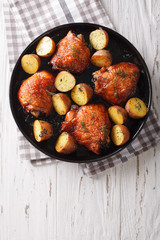 Roast chicken thighs and baby potatoes with maple syrup closeup. vertical top view