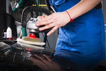 The man is polishing the black car with polish machine.