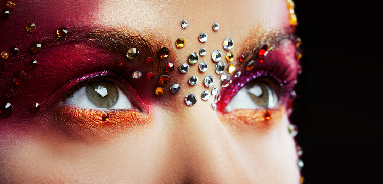 Eyes of a beautiful young woman in a bright designer makeup with rhinestones