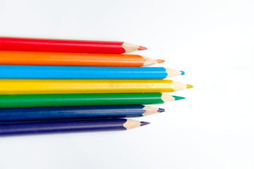 Heap of pencils of rainbow colors on the white surface.