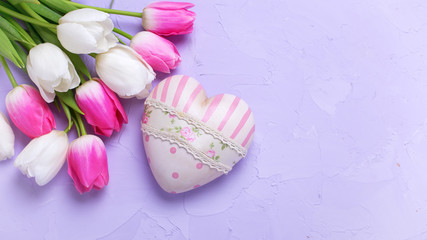 Pink  and white tulips flowers and decorative heart  on violet  textured background.