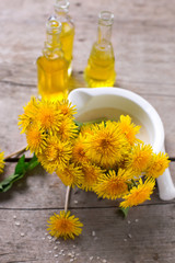 Fresh yellow flowers tussilago in mortar on wooden background.