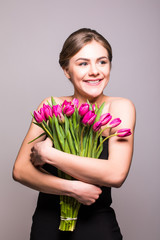 Portrait of beautiful young woman with long hair and glamour makeup. Girl holding tulips. Studio shot.