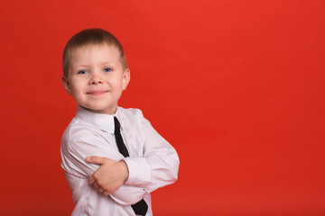 Little boy posing in the studio on a red background.