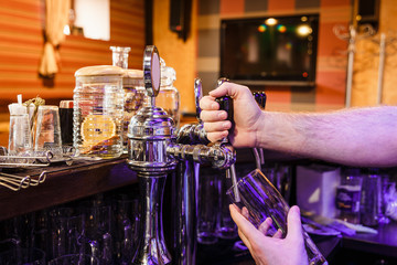 Close-up of bartenders hands pouring beer