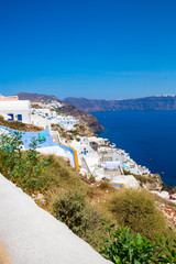 View of Fira town - Santorini island,Crete,Greece. White concrete staircases leading down to beautiful bay with clear blue sky and sea