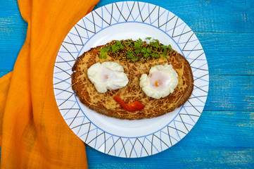 Children's menu: hot sandwich of black rye bread with grated cheese and a poached egg on a plate on a blue wooden background. Kids food. The top view