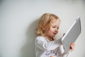 Fototapeta premium Pretty little girl with a Tablet PC. Isolated on white.