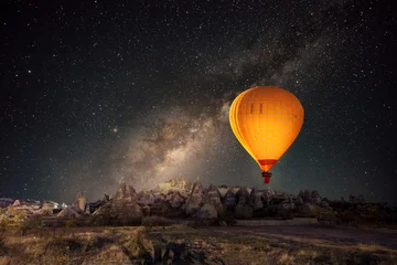 Vlies Fototapete Ballon Heißluftballon fliegt über spektakuläres Kappadokien unter dem Himmel mit Milchstraße und leuchtendem Stern in der Nacht