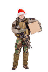 Smiling young soldier with rifle wearing Santa claus cup and holdinga cardbox