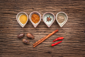 Various herbs and spices in wooden spoons. Flat lay of spices ingredients chilli ,pepper, garlic,dries thyme, cinnamon,star anise, nutmeg, shallot ,bay leaves and fenugreek on wooden background.